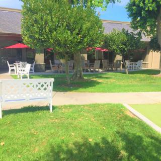 A peaceful outdoor garden area with benches and patio tables under red umbrellas.