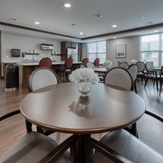 A modern dining area with neatly arranged tables and chairs, featuring a decorative vase in the center.