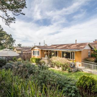 A charming house surrounded by a lush garden under a blue sky.