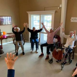 A group of seniors participating in a seated exercise session indoors.