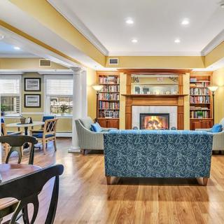 A cozy living room with a fireplace and bookshelves, featuring a blue sofa and warm lighting.