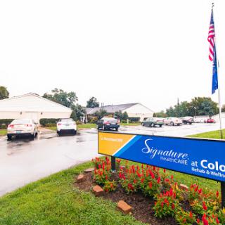 Sign for Signature at Colonnade, showcasing a welcoming entrance on a rainy day.