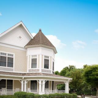 A charming Victorian-style house with a front porch against a blue sky.