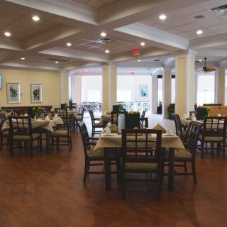An empty restaurant dining area with neatly arranged tables and chairs, featuring elegant lighting and decor.