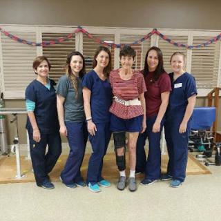 A dedicated team of healthcare professionals posing with a patient during rehabilitation.
