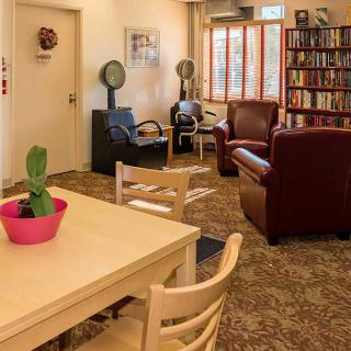 A cozy living room with seating, a bookshelf, and a table with a potted plant.