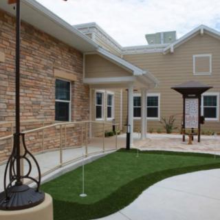 A modern building with a brick exterior, featuring a pathway and ramp leading to the entrance.