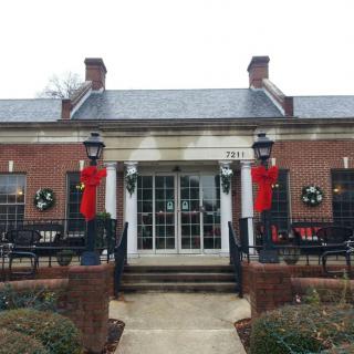 A festive brick building decorated with wreaths and red ribbons, featuring outdoor seating.