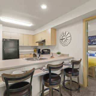 A modern kitchen featuring an open layout with bar stools and essential appliances.