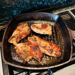 Grilled chicken breasts cooking in a cast iron skillet.