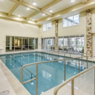A spacious indoor swimming pool with large windows and bright lighting.