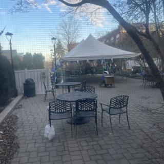 A serene outdoor setting featuring a tent, tables, and chairs under a clear sky.