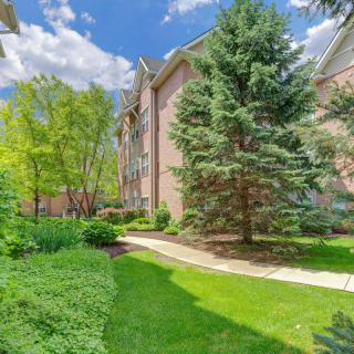 A scenic view of an apartment complex surrounded by lush greenery and a paved pathway.
