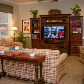 A cozy living room with a plaid sofa, wooden entertainment center, and various decor elements.