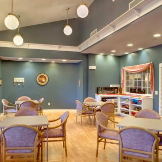 A modern dining area with tables and chairs, featuring decorative lighting.
