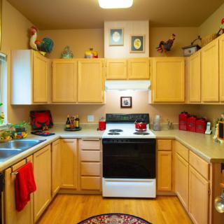 A cozy kitchen with light wood cabinets, a black and white oven, and colorful decorations.