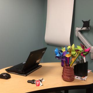 A cozy office workspace featuring a laptop, colorful pinwheels, and a neatly organized desk.