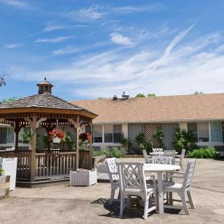 A spacious outdoor area featuring a wooden gazebo and patio furniture under a clear blue sky.