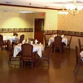 A cozy dining area with tables and chairs, featuring a chandelier and elegant decor.