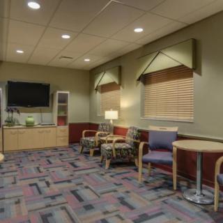A cozy waiting room with comfortable seating, a television, and warm lighting.
