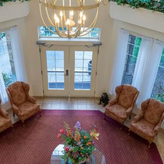 A spacious lobby with elegant seating and a chandelier, featuring ample natural light from large windows.