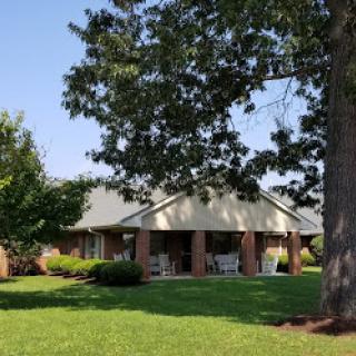 A serene residential home set amidst lush greenery and a clear blue sky.