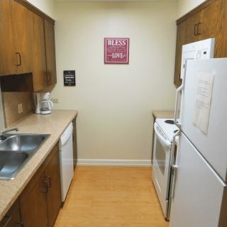 A compact kitchen with wooden cabinets and essential appliances.