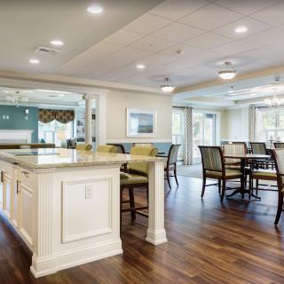 A spacious and modern kitchen with a dining area, featuring wood flooring and bright lighting.