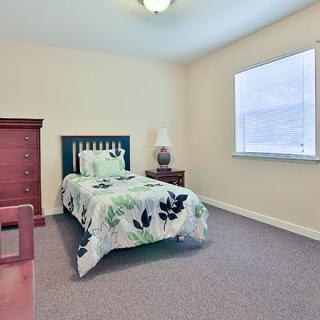 A simple bedroom with a single bed, dresser, and a window providing natural light.