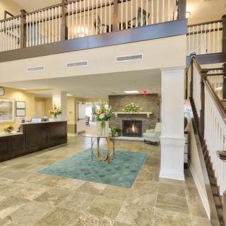 A spacious and modern lobby featuring a reception desk, stylish seating area, and an elegant staircase.