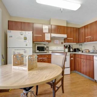 A modern kitchen with wooden cabinets, a round dining table, and various appliances.
