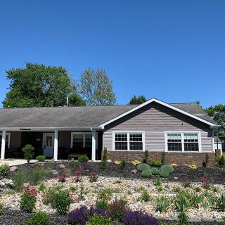 A single-story ranch-style house with a landscaped garden and clear blue sky.