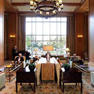 A spacious hotel lobby with large windows, elegant furnishings, and a grand chandelier.