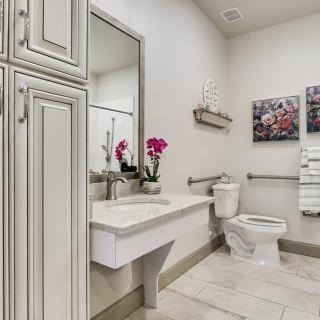 A modern bathroom with a floating sink, mirror, and elegant decor including orchids and artwork.