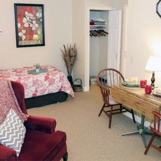 A cozy bedroom with a bed, table, and chair, featuring warm decor.
