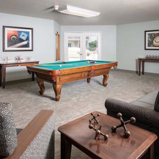 A well-furnished game room featuring a pool table, artwork, and comfortable seating.
