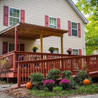 A cozy house with a wooden deck decorated for autumn with pumpkins and flowers.