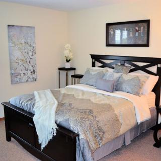 A cozy bedroom with neatly arranged bedding, soft pillows, and elegant wall art.
