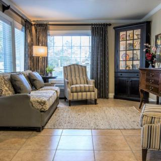 A cozy living room with a sofa, armchair, and large window providing natural light.
