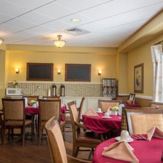 A cozy dining room with neatly set tables and warm lighting.