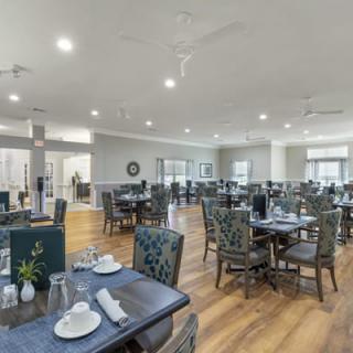 A spacious and well-lit dining room with neatly arranged tables and chairs.