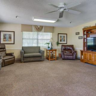 A cozy living room with sofas, chairs, a television, and a large window.