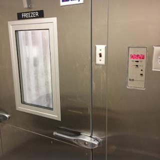 A metallic elevator door featuring a control panel and a small window labeled 'SHELTER'.
