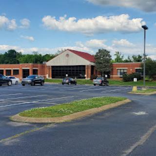 A spacious parking lot in front of a commercial building under a partly cloudy sky.