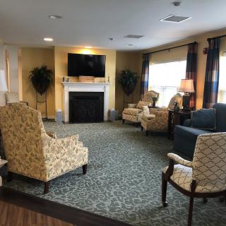 A cozy living room with patterned chairs, a sofa, and a fireplace under a mounted television.