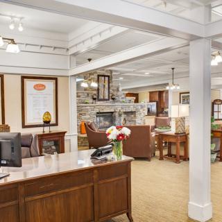 A cozy office lobby with a reception desk, comfortable seating, and decorative elements.