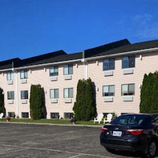 A view of a motel with neatly arranged parking spaces and clear blue skies.