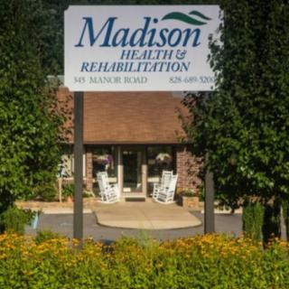 Entrance to Madison Health & Rehabilitation facility with a welcoming sign and garden.