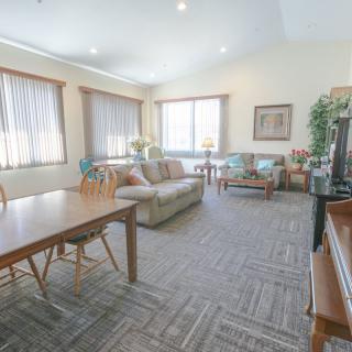A spacious living room with comfortable seating, a large table, and ample natural light from the windows.