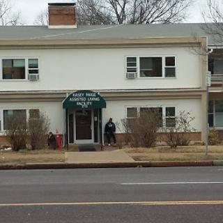 A residential building featuring a green awning over the entrance, surrounded by bushes.